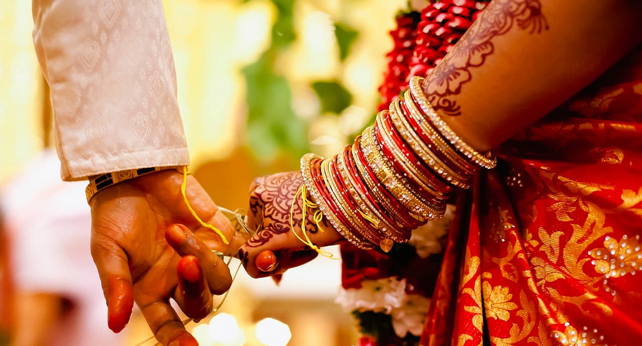 Bride and groom holding hands at their wedding, with mehndi and bangles
